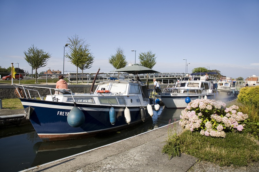 Mensen zitten op een bootje op het kanaal Bossuit-Kortrijk te genieten van het zonnetje.