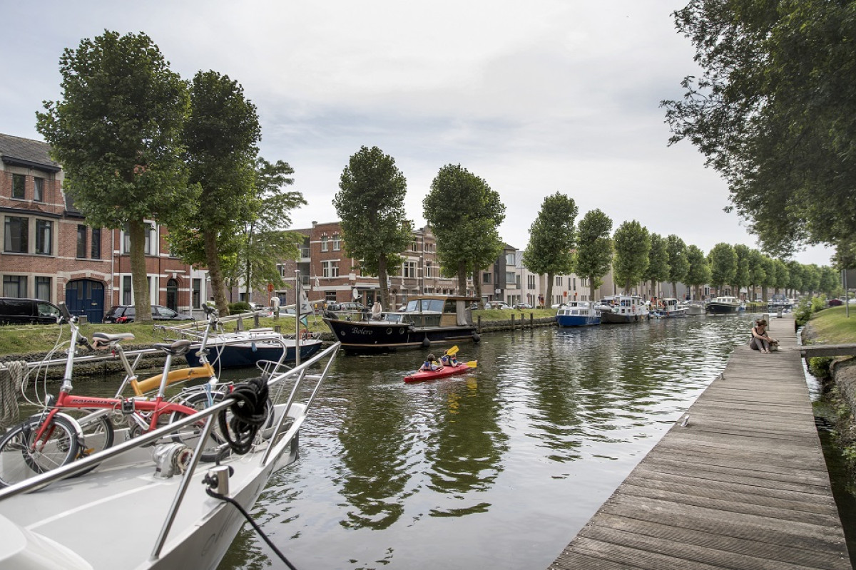 Twee kajakkers op de Durme in Lokeren tussen bootjes aan de steiger.