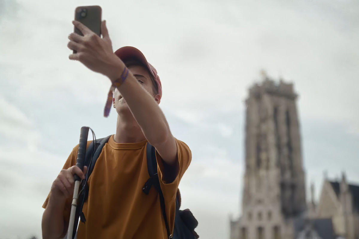 Taking a selfie at Sint-Romboutstoren Person with backpack and cap takes a selfie with a smartphone; a tall tower in the background.
